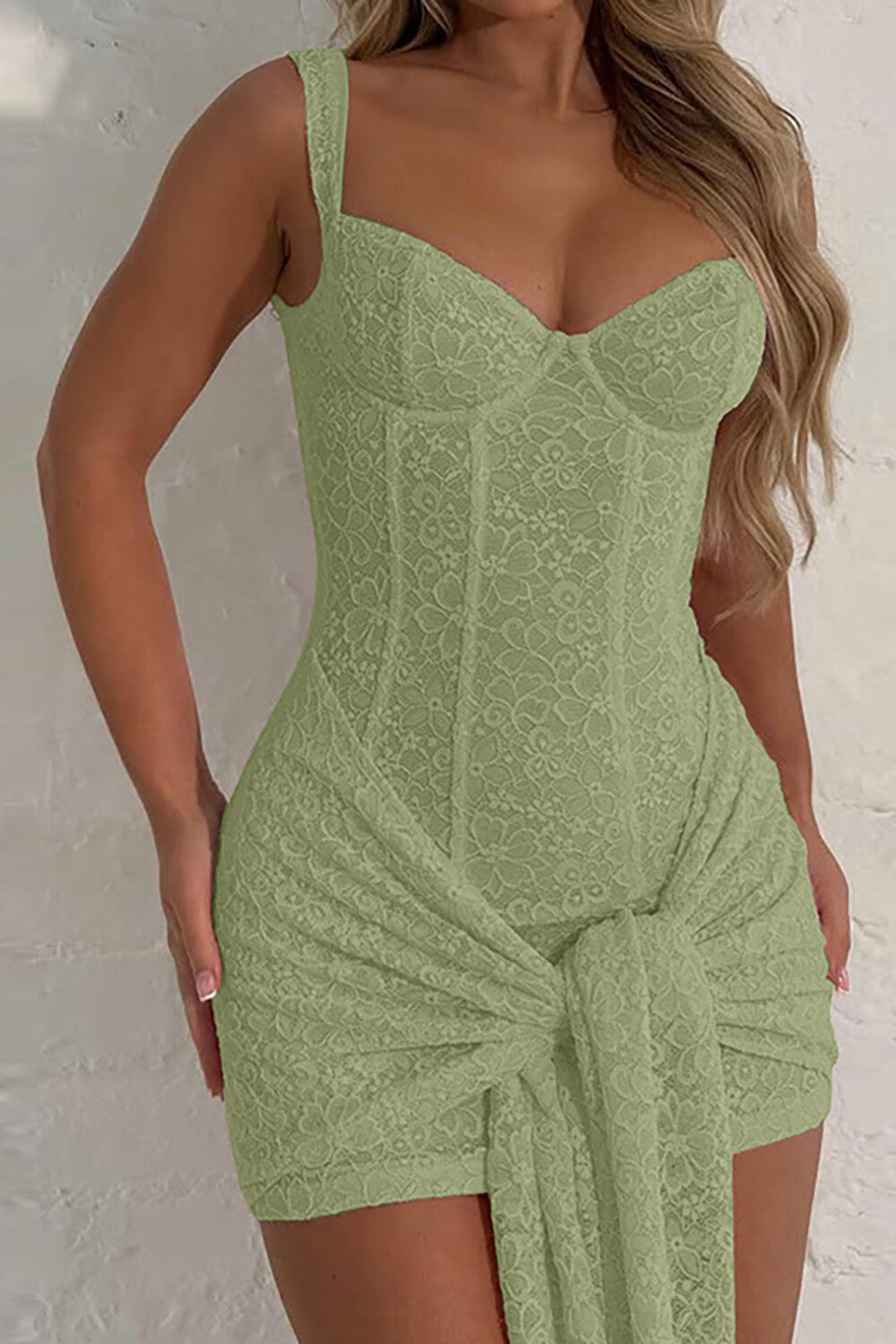 Close-up of a light green lace corset dress with a draped skirt