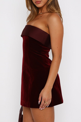 Side profile of a woman in a burgundy velvet strapless mini dress