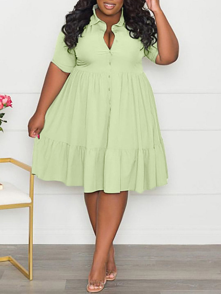 Woman wearing a light green short-sleeved collared dress with a tiered hem and button-down front.
