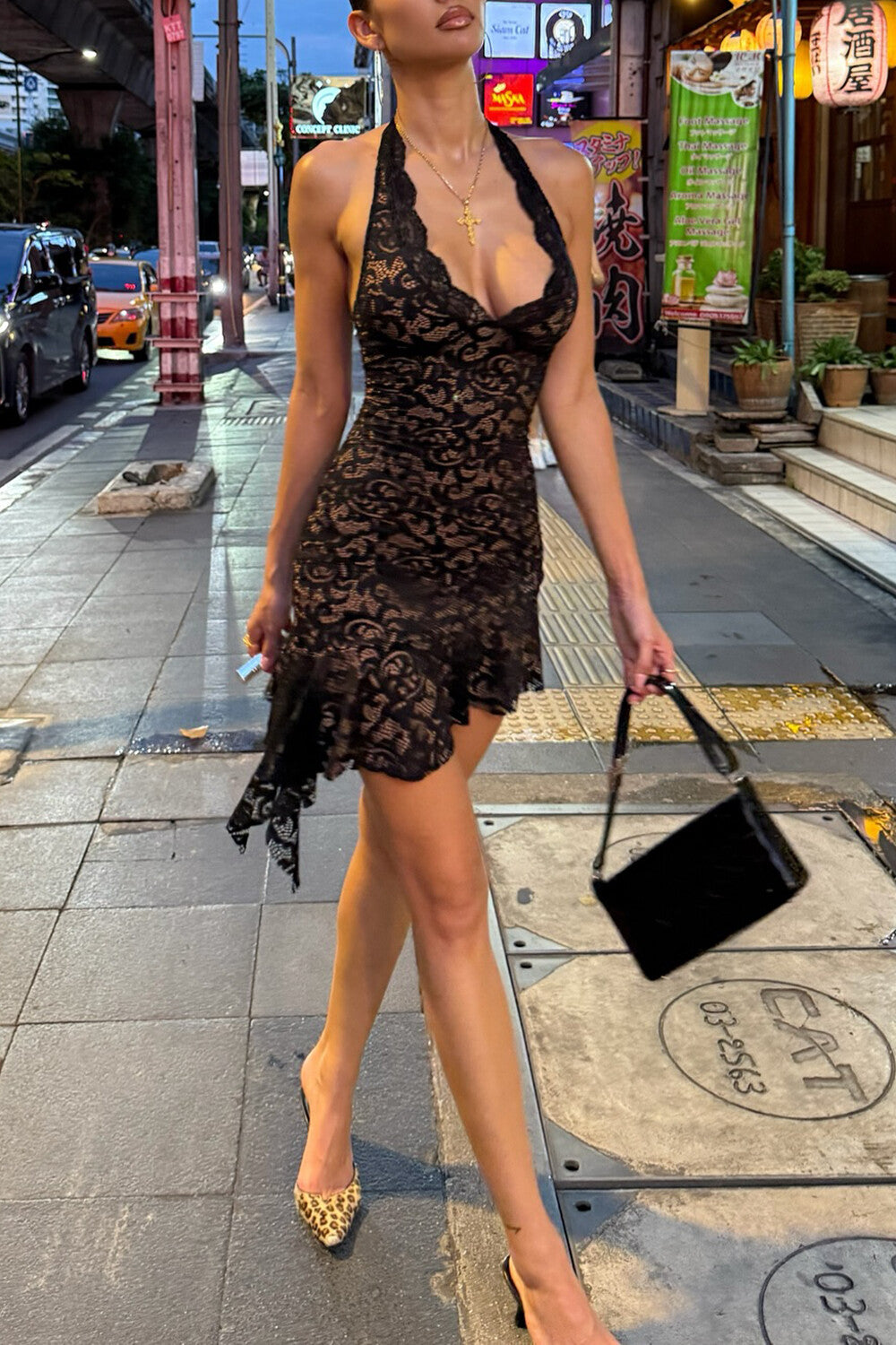 woman walking on a sidewalk in a black lace halter dress