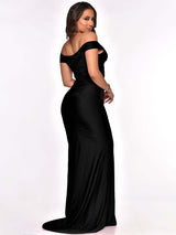 Side view of a woman in a black off-the-shoulder ruched formal gown with a high slit
