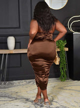 Back view of a woman wearing a brown satin ruched halter neck sheath dress.