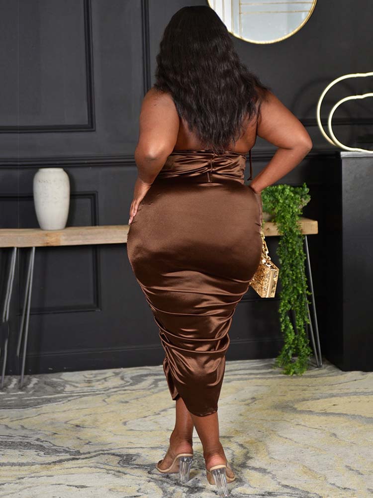 Back view of a woman wearing a brown satin ruched halter neck sheath dress.