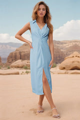 Woman in a light blue satin dress with a V-neck, collared neckline, sleeveless design, twisted front detail, and a high slit, standing in a desert landscape.