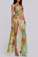 Full-length view of a woman in a flowing sheer maxi dress with an abstract print and asymmetrical neckline.