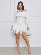Model wearing a white off-the-shoulder eyelet lace mini dress with bell sleeves and tiered skirt, holding a clear clutch.