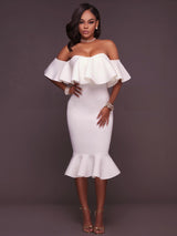 Woman wearing a white off-the-shoulder ruffle dress and gold heels, front view