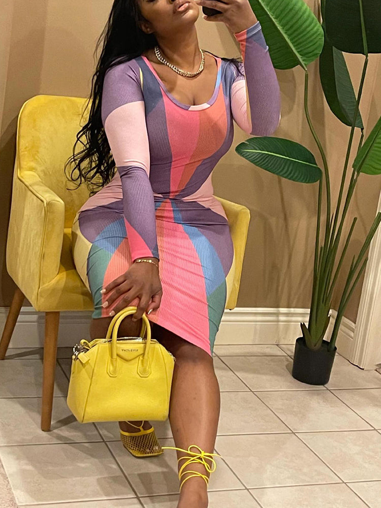 Woman sitting in a yellow chair, showcasing a long-sleeved, bodycon midi dress featuring a geometric design, with a yellow handbag on her lap.