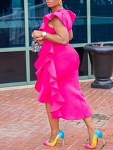 Rear side view of a woman in a fuchsia pink ruffled dress, emphasizing the back and the flow of the ruffles.
