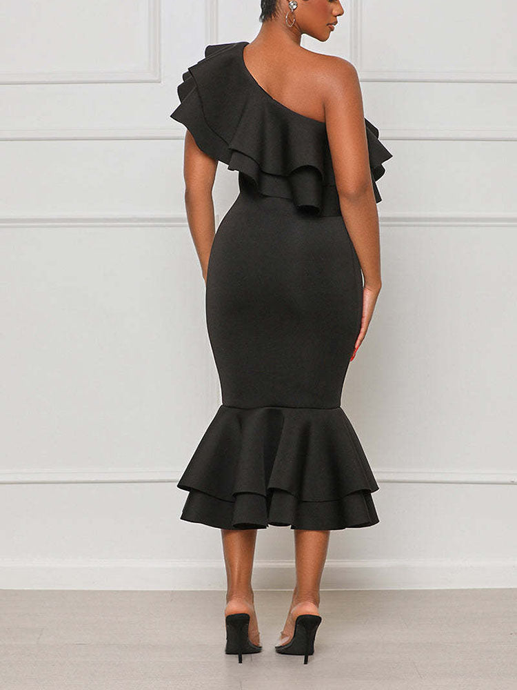 Back view of a woman in a black one-shoulder midi dress with ruffle details and a mermaid hem.