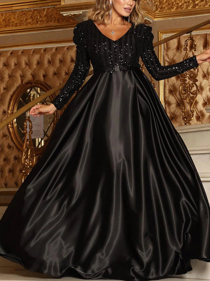 Woman wearing a black long-sleeved A-line formal dress with a sequined bodice and a satin skirt.
