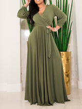 Woman wearing an olive green maxi dress with a wrap neckline and long sleeves.