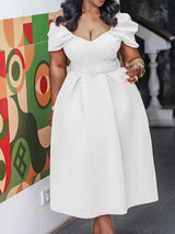 Woman in a white off-the-shoulder dress with a belted waist and pleated skirt, showing the detail of the neckline and sleeves.