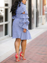 Back view of a woman wearing a blue and white striped dress with ruffled sleeves.