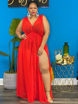 Woman wearing a red sheer maxi dress with high leg slits, front view