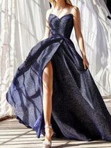 Model wearing a navy blue sparkly strapless ball gown with a high slit, standing in natural light.