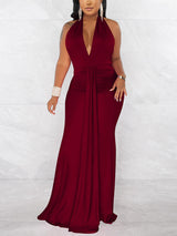 Woman wearing a long deep red halter neck dress with a deep V-neck and ruched waist