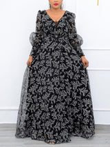 Woman wearing a long black and white floral print gown with sheer puff sleeves and a V-neckline.