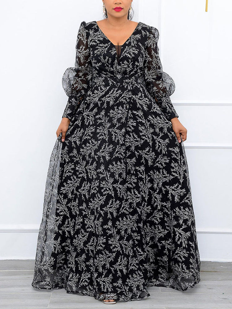 Woman wearing a long black and white floral print gown with sheer puff sleeves and a V-neckline.