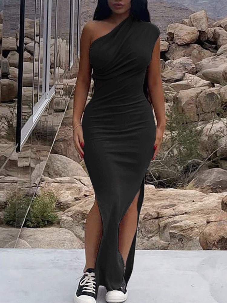Woman wearing a black one-shoulder, draped maxi dress with a high slit and sneakers.