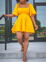 Woman walking down stairs in a yellow two-piece set with a square neckline and puff sleeves.