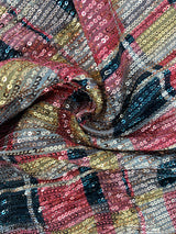 Close-up of the sequined fabric with a plaid pattern in shades of red, gold, black, and cream.