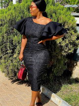 Woman wearing a black one-shoulder midi dress with ruffle sleeves and a rose jacquard pattern, holding a red circular handbag.