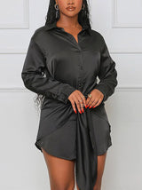 Close-up of a black satin shirt dress with a tie waist.