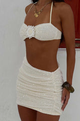 Back view of a woman in a white sequined mini dress with a halter neckline and cut-out details.