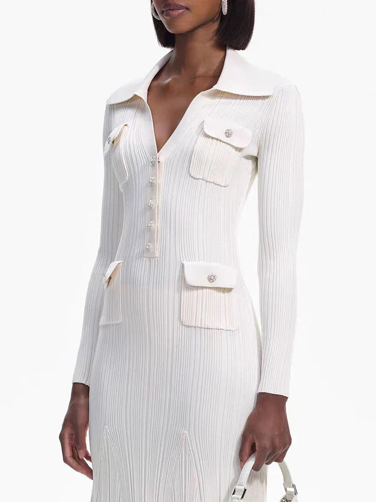 Close-up of the bodice of a cream-colored long-sleeved knit dress featuring a collared neckline, button-up front, and dual chest pockets with decorative buttons.