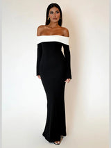 Woman wearing a black off-the-shoulder floor-length dress with a white trim, standing against a white background.