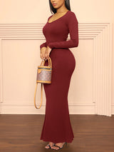 Woman wearing a long-sleeved, ribbed knit maxi dress in burgundy, side view.