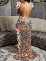 Woman in a rose gold sequin and feather gown with an asymmetrical hemline, showcasing the back view with an open back.