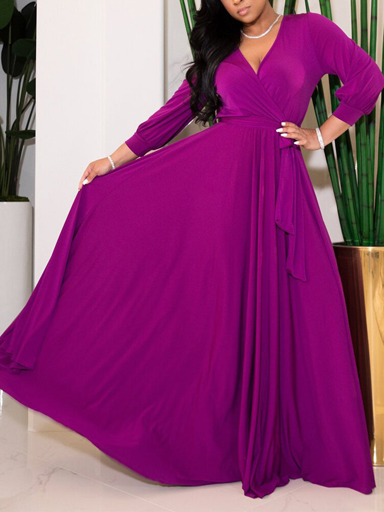 Woman twirling in a vibrant purple maxi dress with a wrap neckline and long sleeves.