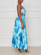 Woman wearing a blue tie-dye one-shoulder pleated maxi dress from the side, showing cut-out detail.