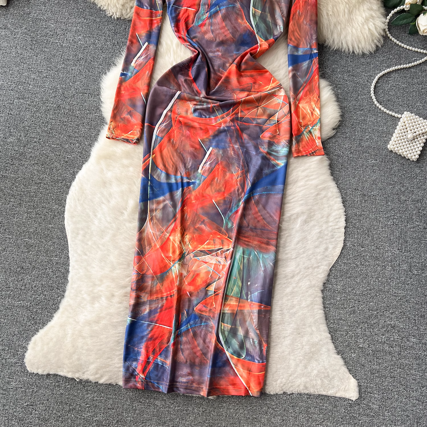 View of the lower portion of the long-sleeved abstract print maxi dress, emphasizing the side slit and flowing fabric.