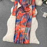 View of the lower portion of the long-sleeved abstract print maxi dress, emphasizing the side slit and flowing fabric.