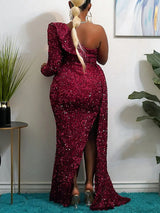 Back view of a woman in a floor-length, one-shoulder, sequined gown with a high slit in red, showing the train.