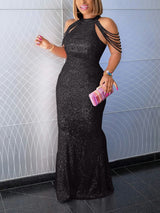 Woman wearing a black sequined mermaid gown with a halter neckline, standing indoors.