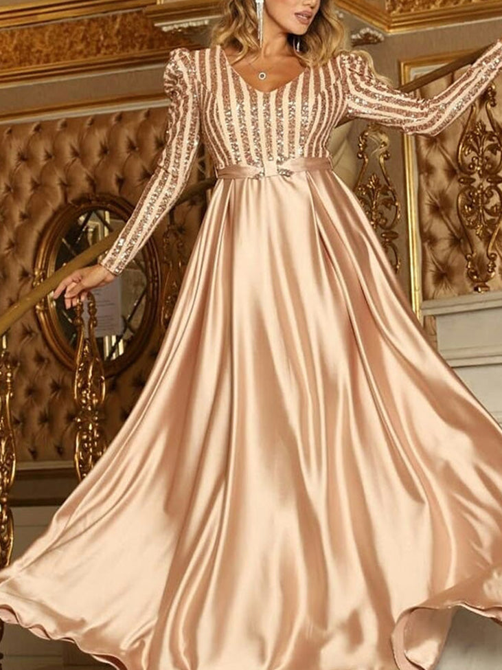 Woman wearing a champagne long-sleeved A-line formal dress with a sequined striped bodice and a satin skirt.