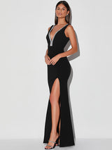 Side view of a woman in a black maxi dress with a V-neckline and high slit.