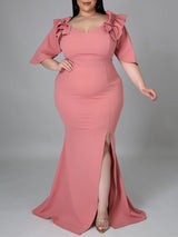 Woman wearing a pink mermaid gown with ruffled neckline and high slit