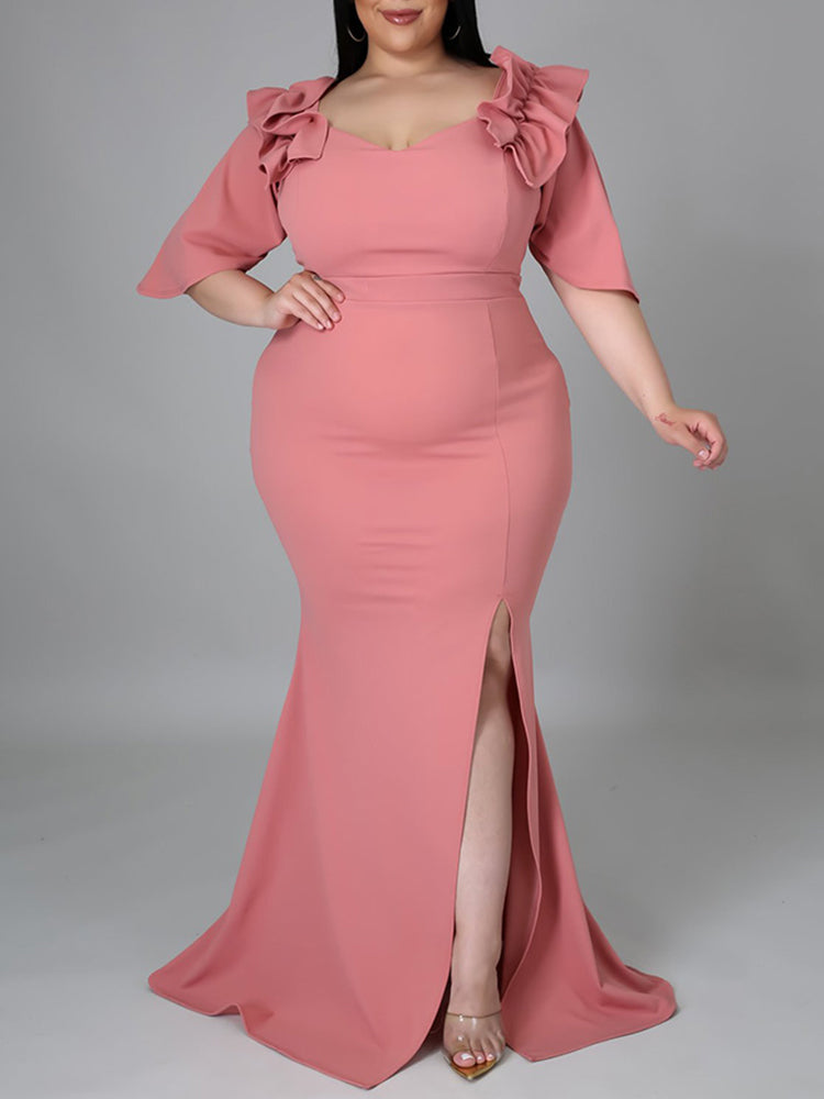 Woman wearing a pink mermaid gown with ruffled neckline and high slit