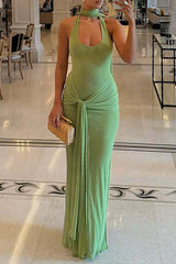 Woman wearing a lime green halter maxi dress with a tie-front detail and high slit, posing indoors in a lobby.