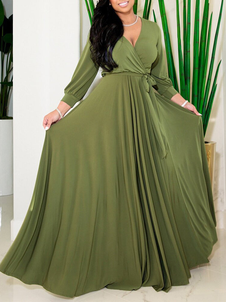 Woman posing in a deep green maxi dress with a wrap neckline and long sleeves.