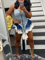 Woman taking a mirror selfie in a denim romper with a zippered front and ruffled hem.
