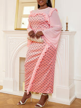 Woman holding a clutch while wearing a pink patterned dress with a ruffled side slit.