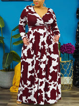 Woman with hands in pockets wearing a burgundy and white cow print maxi dress.