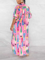 Back view of a woman wearing a long, pink collared shirt dress with a colorful graphic print of people.