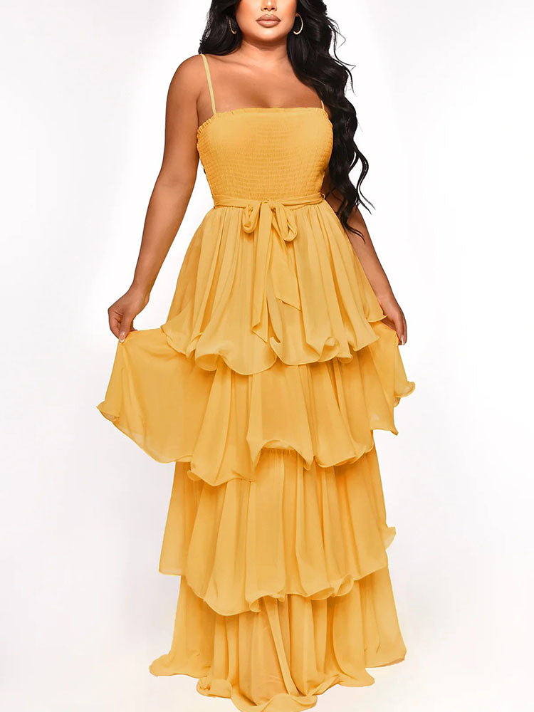 Woman wearing a flowy yellow tiered maxi dress with spaghetti straps and a tie waist.